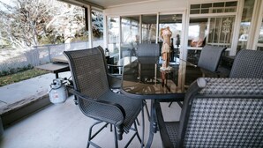 A covered patio with outdoor furniture, including a glass table and chairs, and a propane tank on the ground. - Family FUN at the Homestead with Pool & Ping Pong, Karaoke & more! Great Value! (Brigham City)
