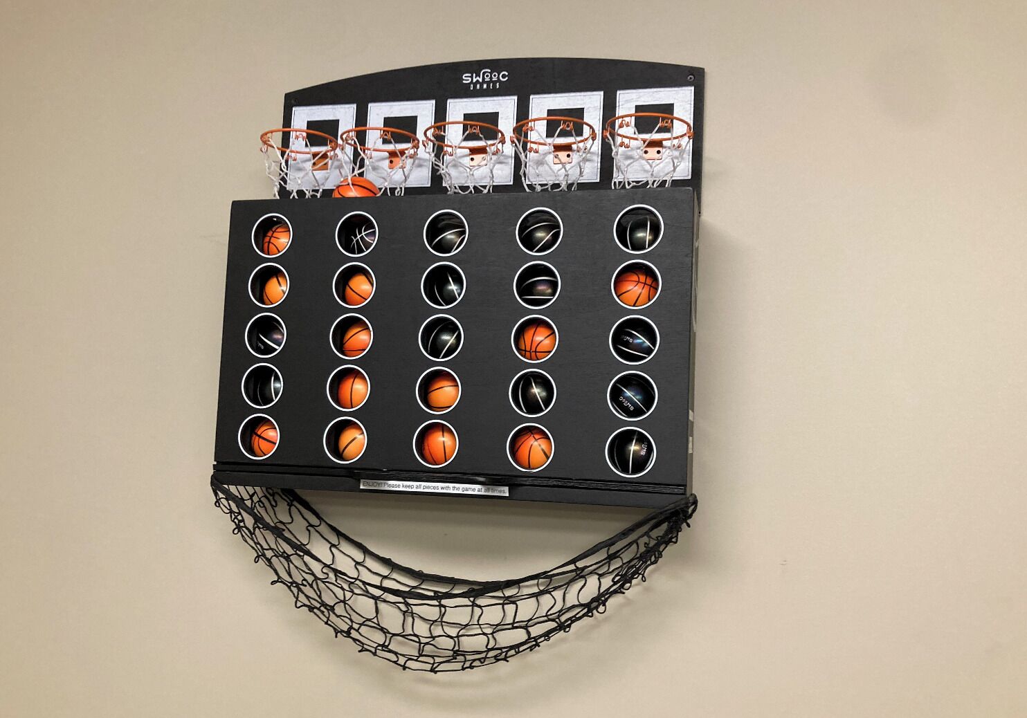 Un panier de basket fixé au mur, avec plusieurs ballons de basket dans la zone du panier.