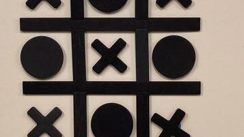 Un tablero de tres en raya con fichas negras de X y O sobre una pared color beige.