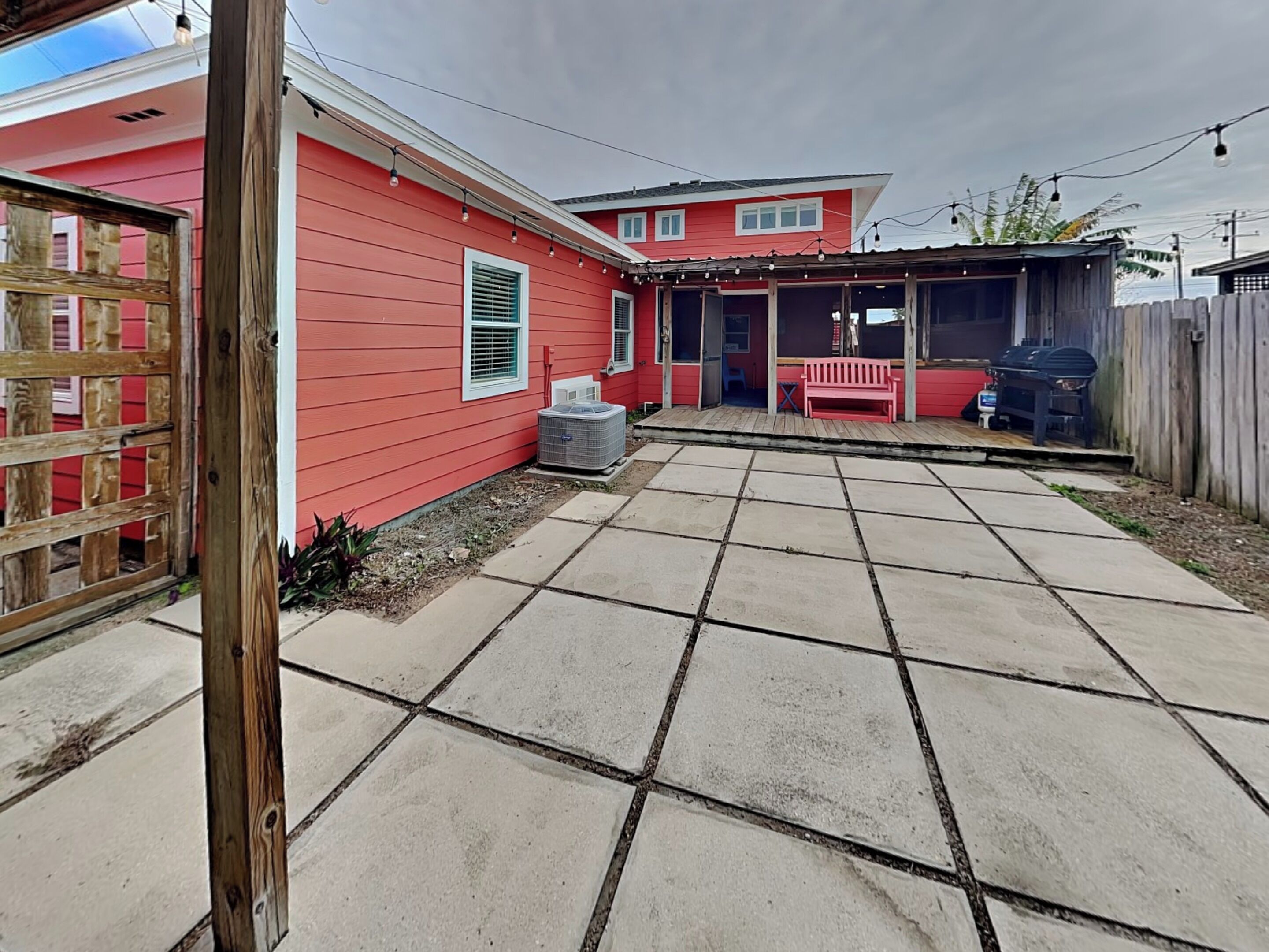 Une maison rouge avec un patio, une clôture en bois et un barbecue.