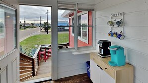 Uma cozinha pequena com cafeteira, pia e janela com vista para a rua.