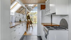 A modern kitchen with white cabinets, a gas stove, and a skylight. - 4 bedroom amazing home in Glesborg (Glesborg)