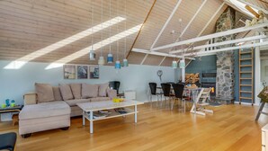 A spacious loft with a high ceiling, a stone fireplace, and a dining area with modern furniture. - 4 bedroom amazing home in Glesborg (Glesborg)