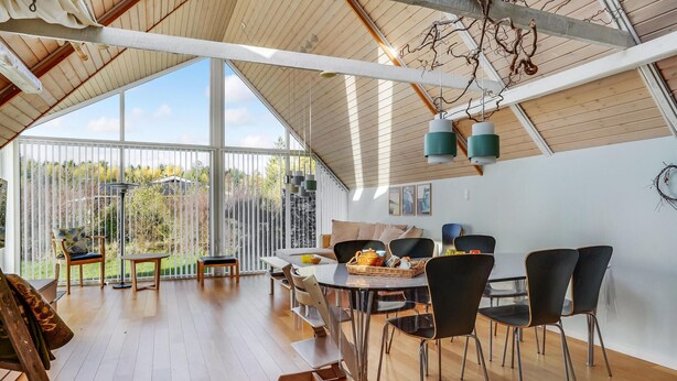 A spacious room with a high ceiling, large windows, and a dining area with modern chairs and a table. - 4 bedroom amazing home in Glesborg (Glesborg)