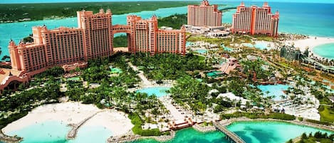 Resort com vários edifícios altos, área de piscina central e praia.