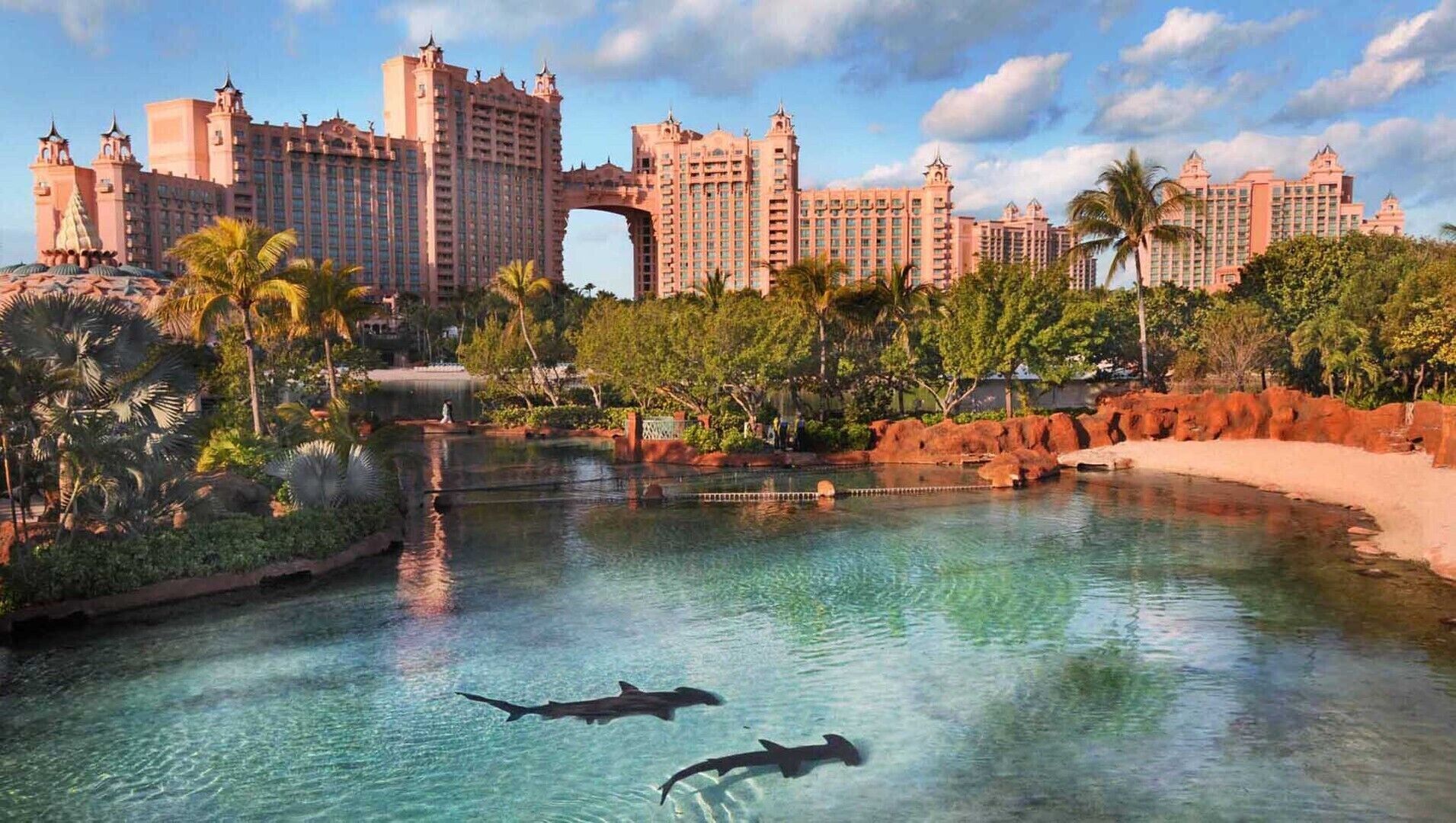 A large hotel complex with a central water feature and two sharks swimming.
