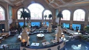 A spacious indoor area with multiple dining tables and chairs, large windows, and decorative columns. - 2 Bedroom Lock-out - Harborside Resort at Atlantis - Full Resort Access (Paradise Island)