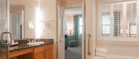 A hotel bathroom with a sink, mirror, and bathtub.