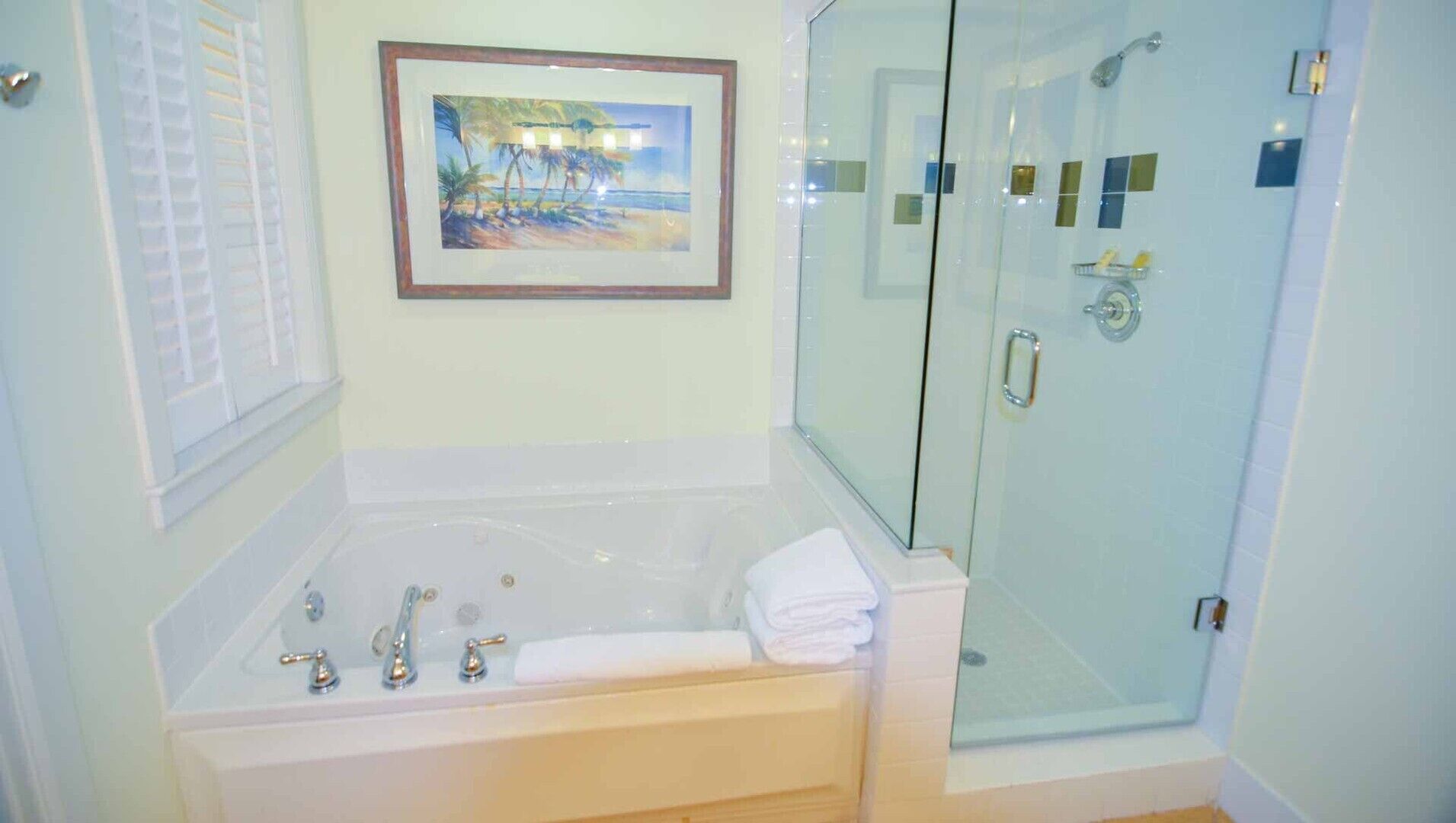 A bathroom with a bathtub, a glass-enclosed shower, and a framed picture on the wall.