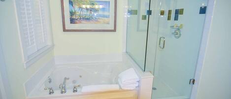 Ein Badezimmer mit Badewanne, einer Duschkabine und einem gerahmten Bild an der Wand.