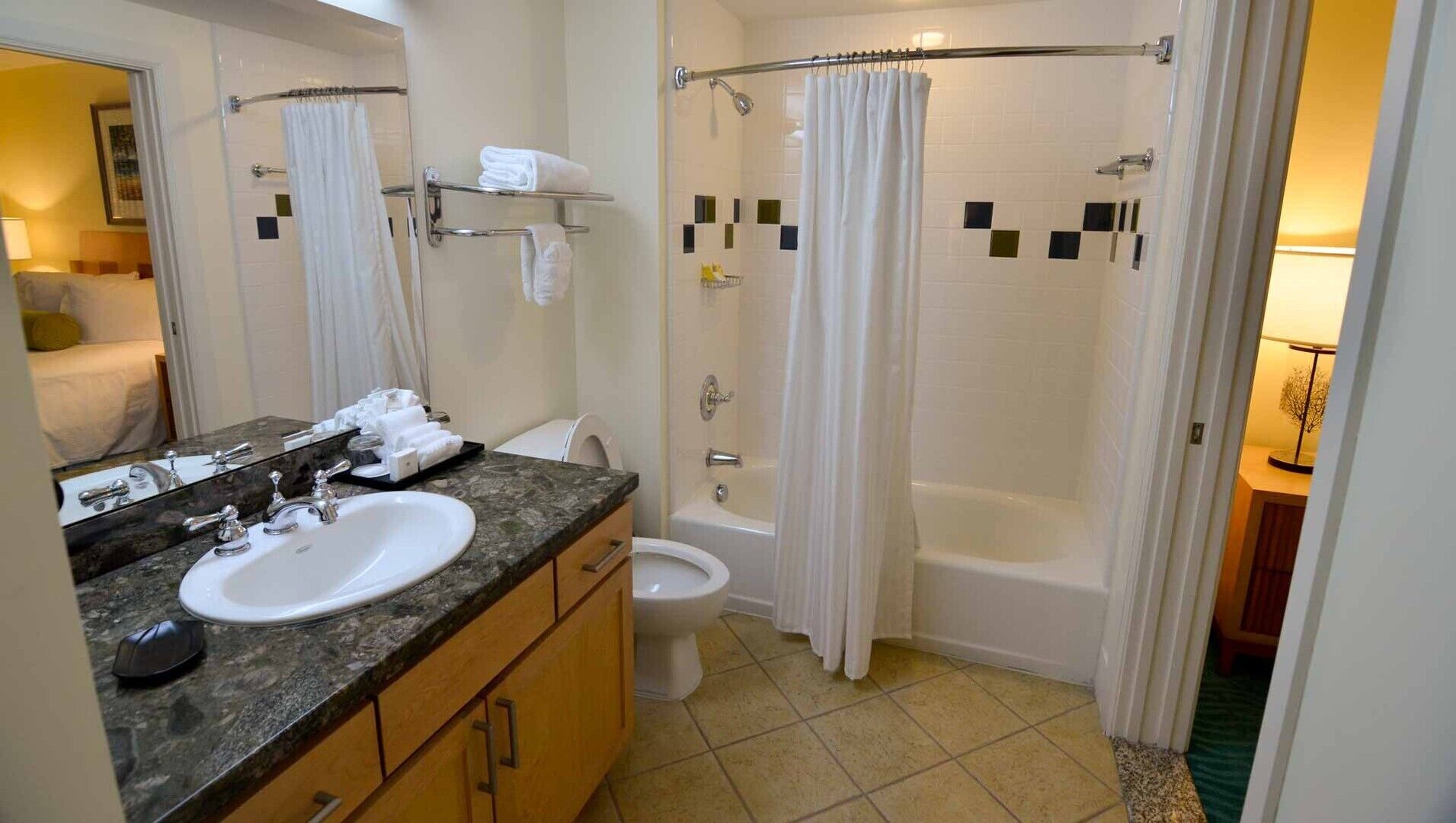 Un baño con lavamanos, espejo, inodoro y zona de ducha.