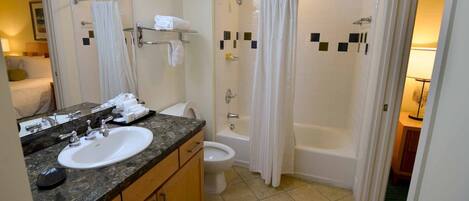 Un baño con lavamanos, espejo, inodoro y zona de ducha.
