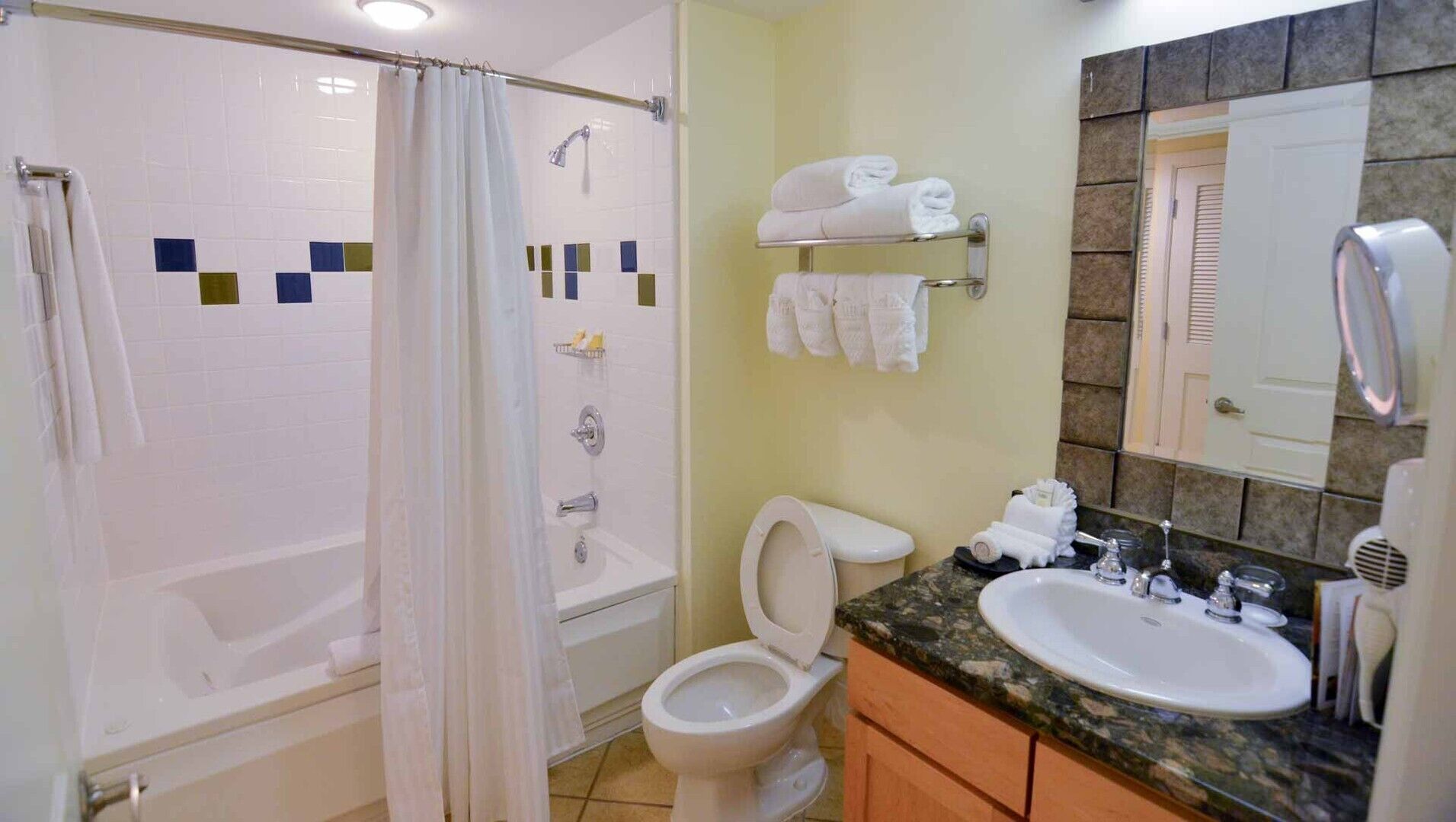 A bathroom with a shower, toilet, sink, and towel rack.