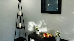 Una habitación con una consola negra, una lámpara de pie y dos plantas en macetas.