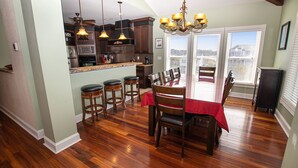 A kitchen with wooden cabinets, a bar area, and a dining table with chairs. - Soundfront, Sound Views, Private Dock, Rec Room, COL21, Warrens Sound Retreat (Kill Devil Hills)