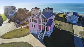 A two-story house with a balcony and a garage, located near a body of water. - Soundfront, Sound Views, Private Dock, Rec Room, COL21, Warrens Sound Retreat (Kill Devil Hills)