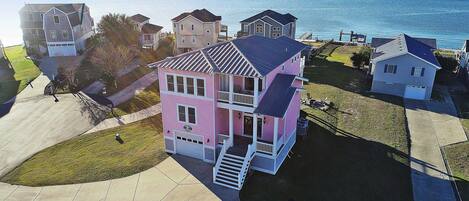 A two-story house with a balcony and a garage, located near a body of water.
