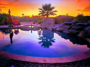 Ein Swimmingpool mit einer Palme und einem Liegestuhl im Hintergrund.
