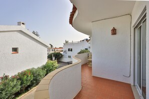 A narrow outdoor corridor with white walls and terracotta flooring, leading to a door with a small decorative lantern. - CoolHouses Algarve Luz | Casa Isabell T1 (Luz)