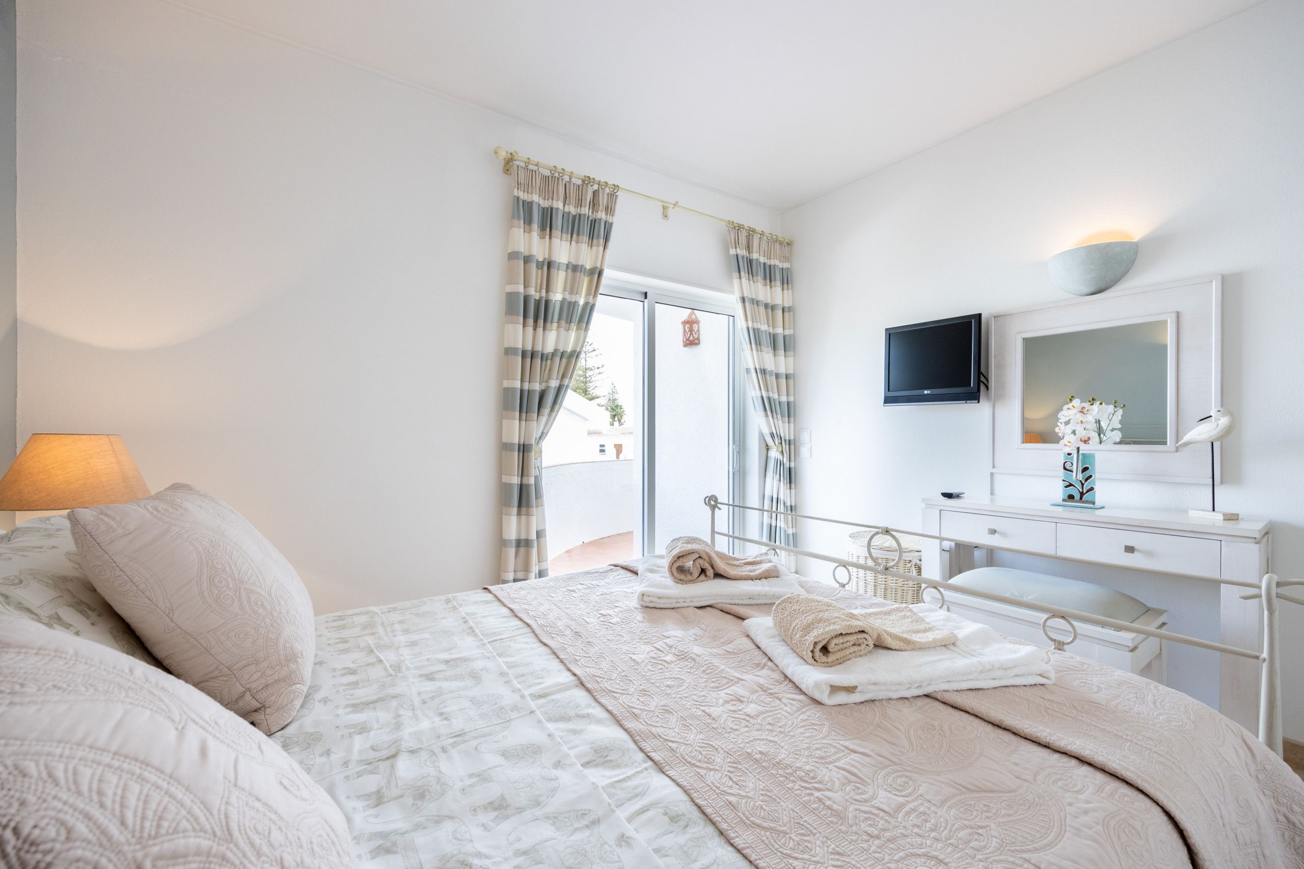 Ein Schlafzimmer mit einem Bett, einem Schreibtisch, einem Fernseher und einem Fenster mit Vorhängen.