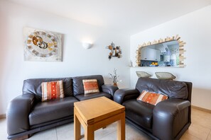 A modern living room with a dark leather sofa, a wooden coffee table, and a decorative wall piece. - CoolHouses Algarve Luz | Casa Isabell T1 (Luz)