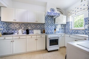 A kitchen with white cabinets, a built-in oven, and a window with a view of greenery.
