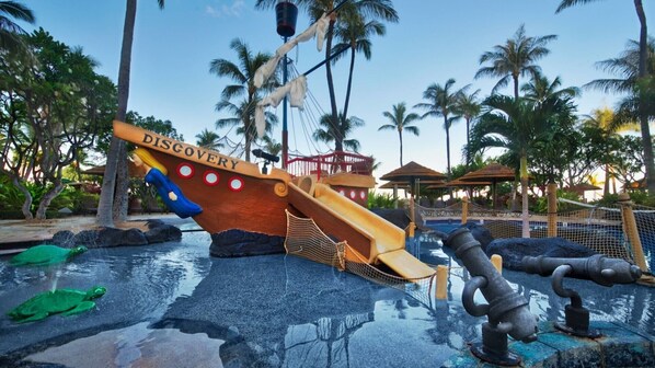 A water play area with a ship-themed slide and a pool with a turtle decoration.