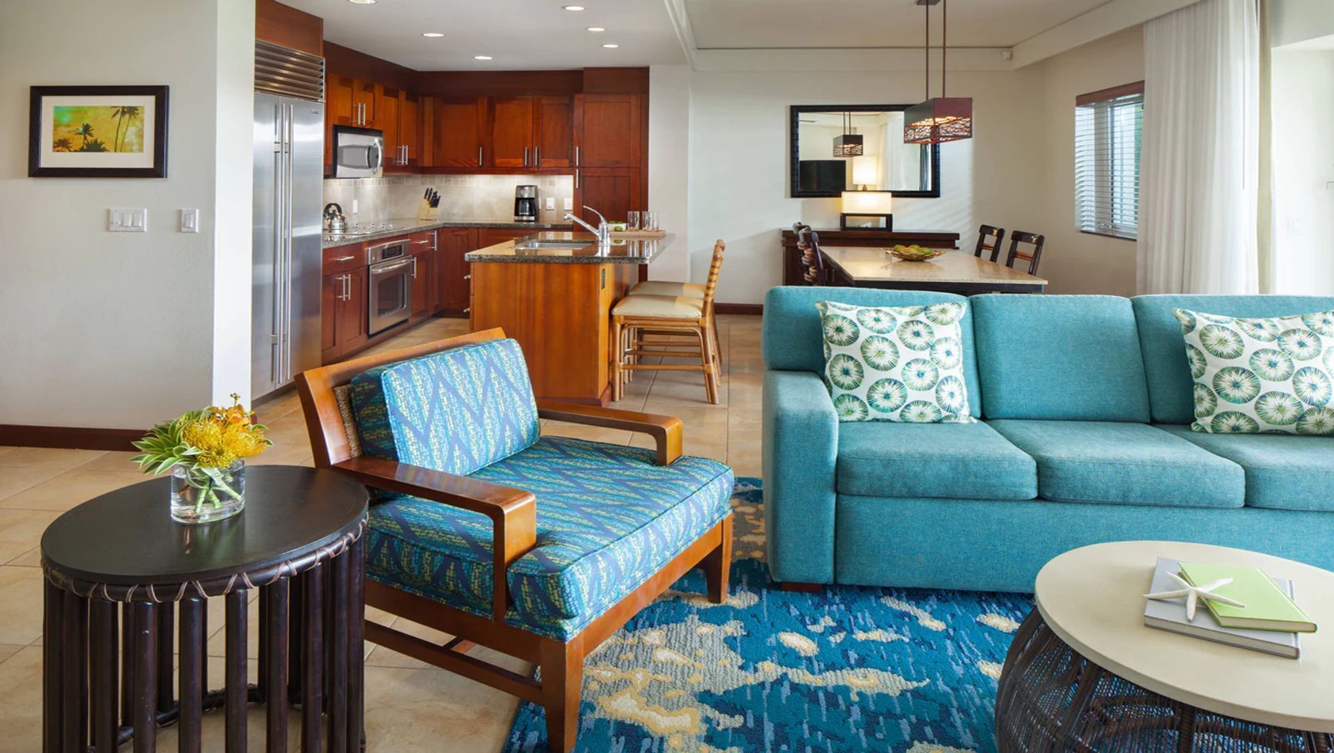 A modern living room with a blue sofa, a wooden armchair, and a dining area with a table and chairs.