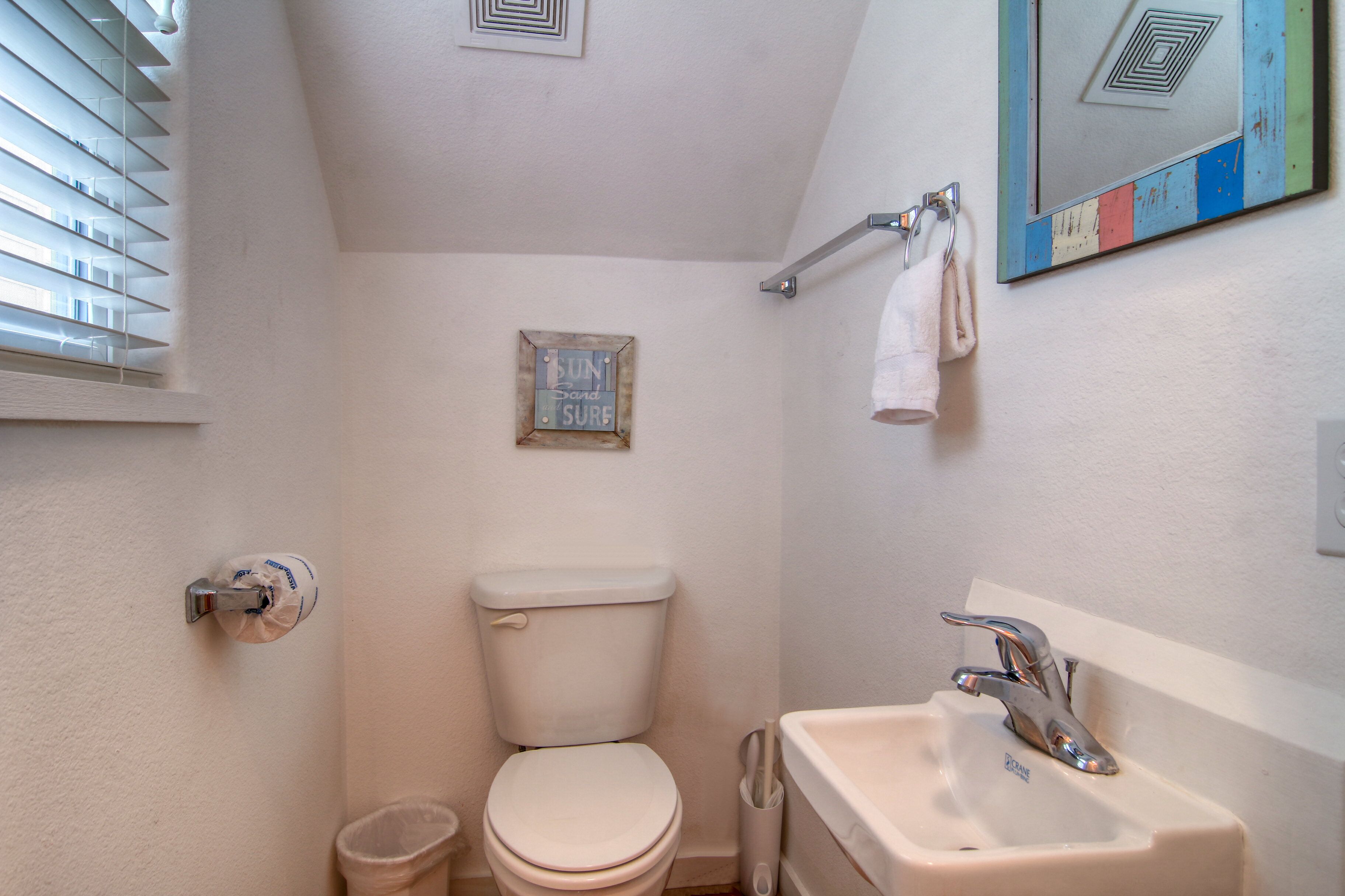 A small, clean bathroom with a toilet, sink, and towel rack.