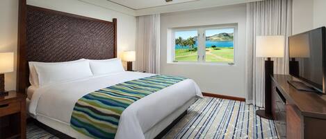 A hotel room with a large bed, a ceiling fan, a TV, and a window with a view of a golf course.