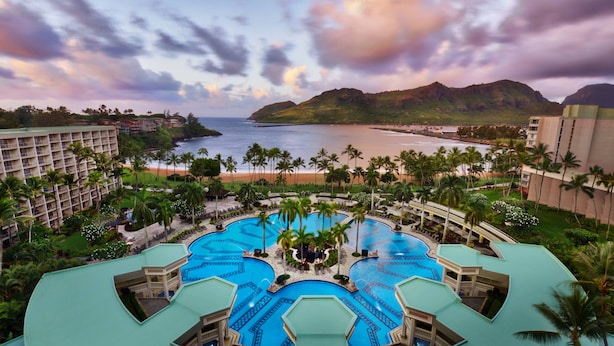 Un resort con varias piscinas, una playa y palmeras.