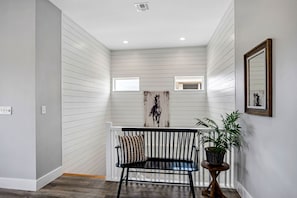 Stylish hallway with a bench, potted plant, and abstract art.