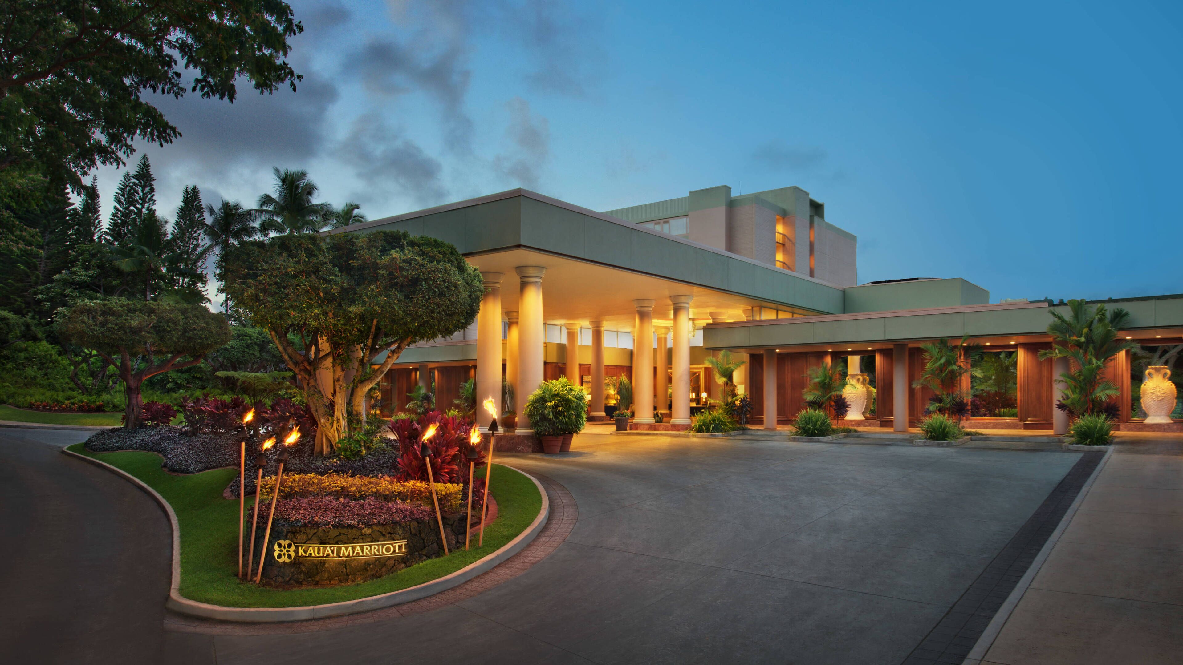 A modern hotel with a spacious entrance, a well-maintained garden, and a prominent sign.