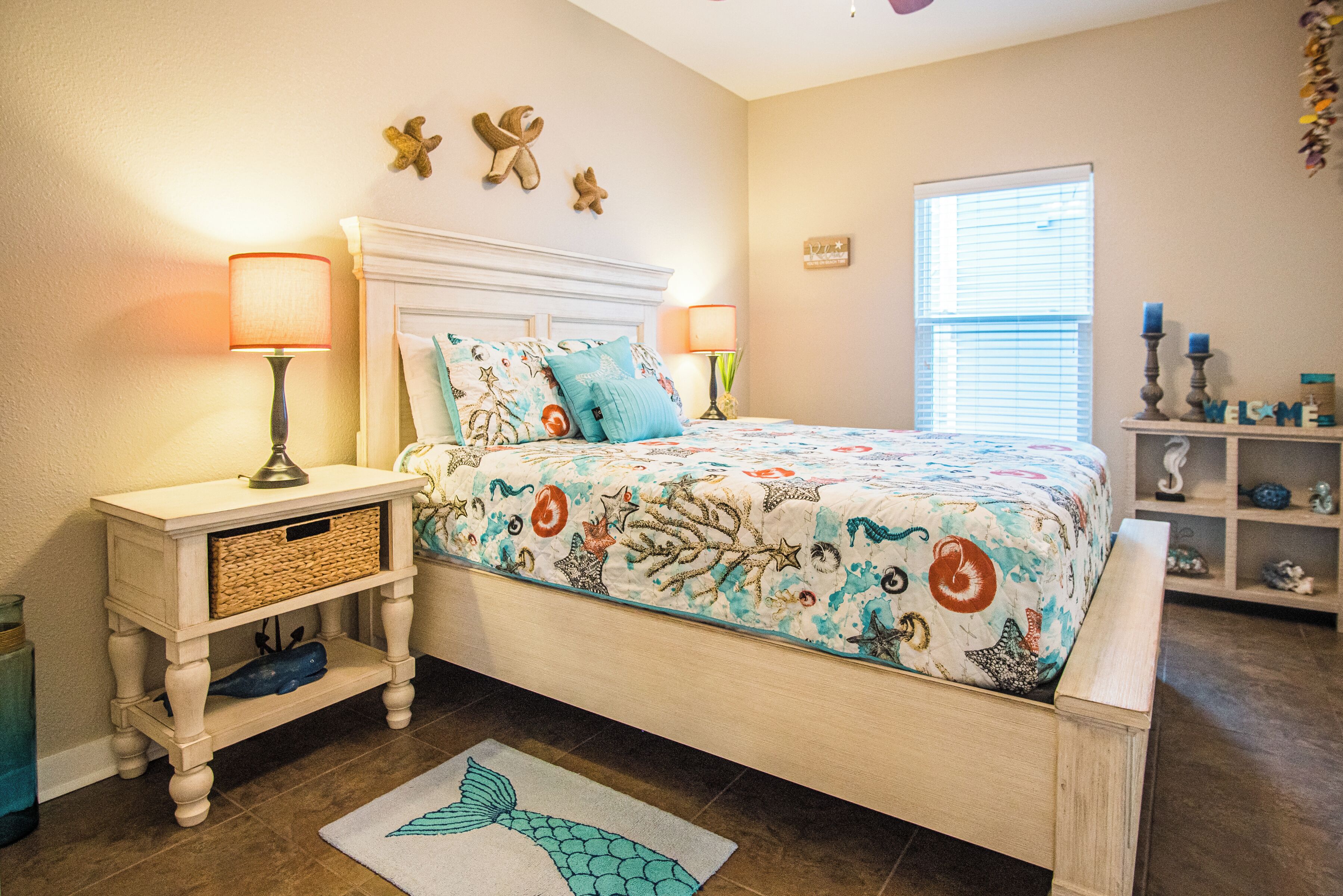 A bedroom with a bed, nightstands, a decorative wall, a window, and a shelf with items.