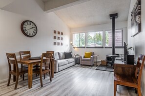 En stue med et træspisebord, stole, en sofa, en pejs og et ur på væggen.