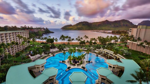 Un resort con varias piscinas, una playa y palmeras.