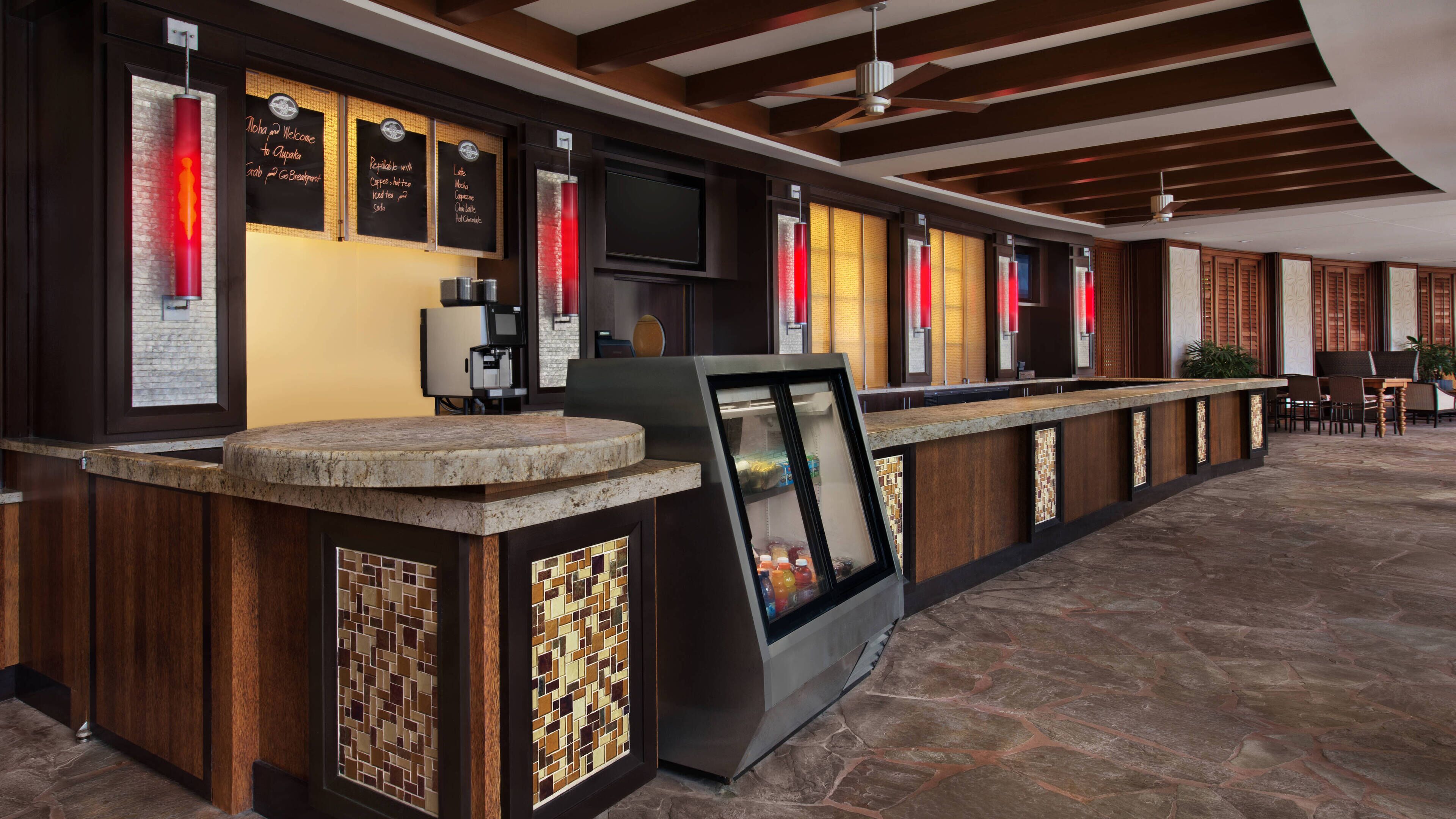 A modern bar area with a stone countertop, a coffee machine, and a menu board displaying various drink options.