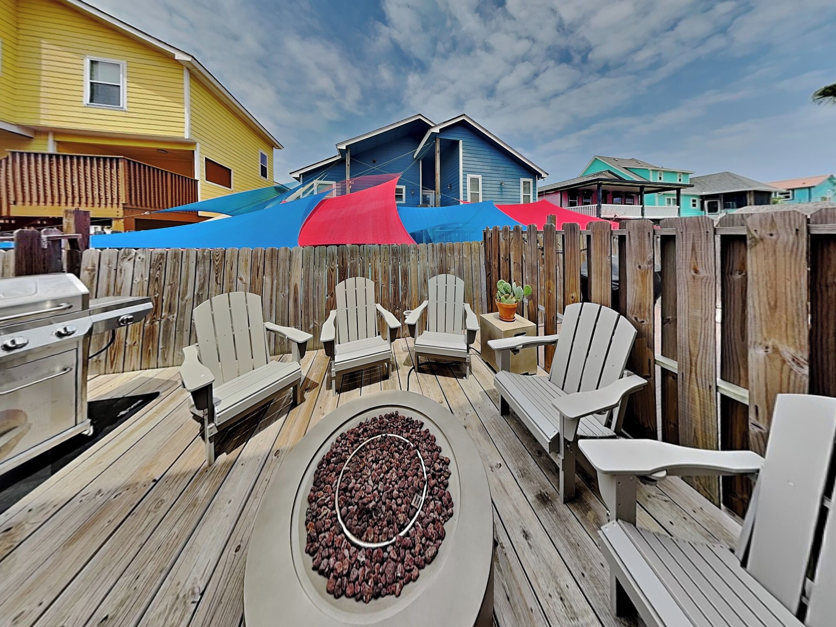 A deck with Adirondack chairs, a grill, and a fire pit.