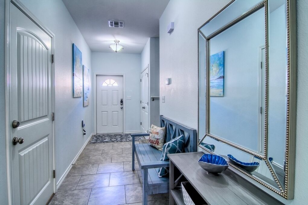 A hallway with a bench, a mirror, and a door.