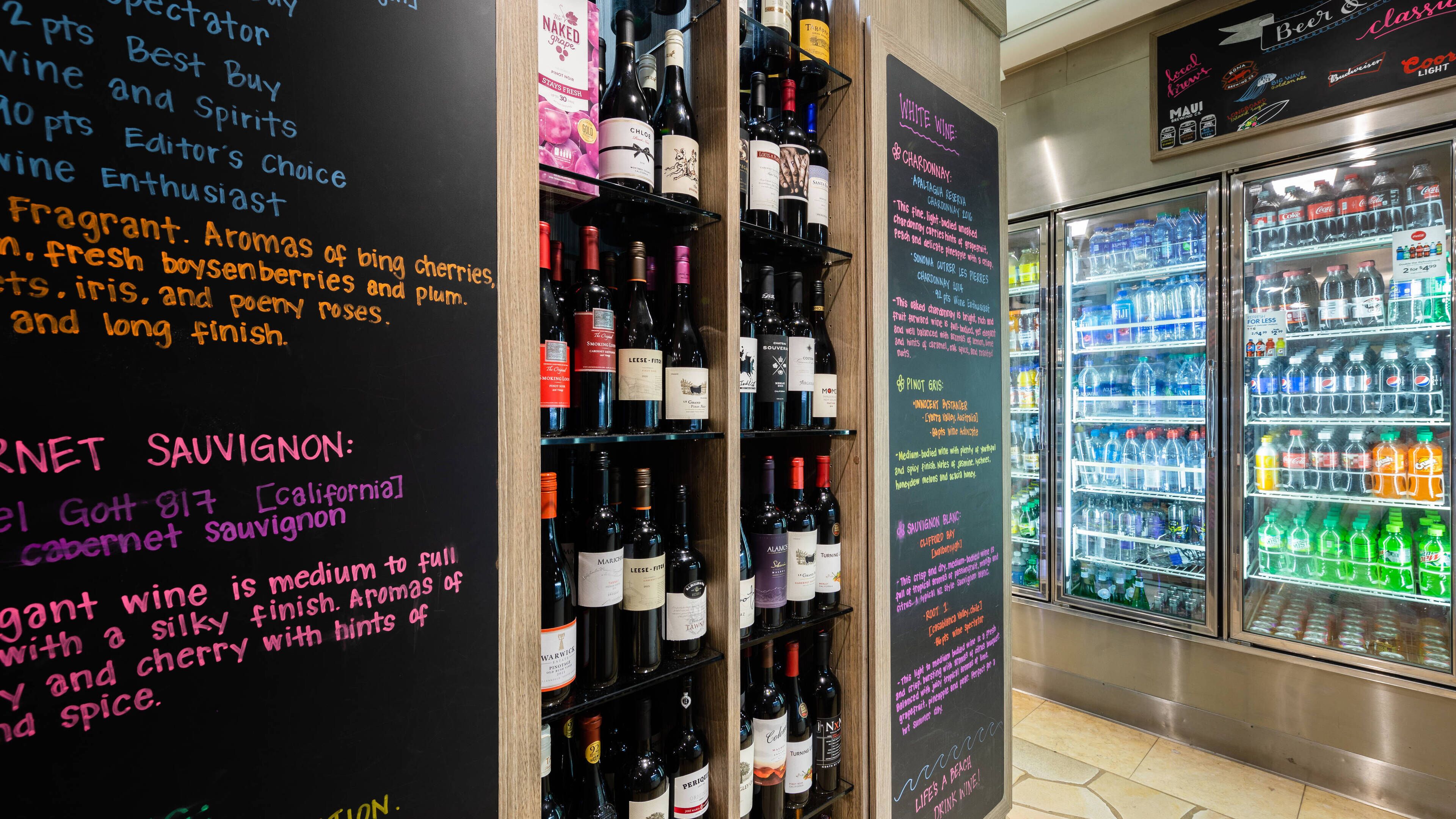 A wine and beverage display area with various bottles and a refrigerator.