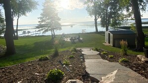 A landscaped garden with a pathway leading to a dock, surrounded by trees and a view of the water.