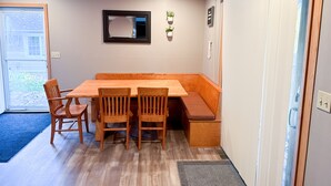 A dining area with a wooden table and chairs, a ceiling fan, a potted plant, and a sliding door.
