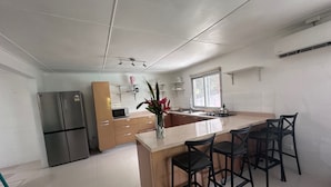 Una cocina moderna con una isla central, taburetes de bar, un refrigerador y un microondas.