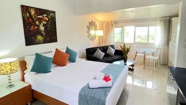 Habitación de hotel con una cama grande, un escritorio, una silla, un ventilador de techo y una ventana.