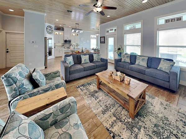 A spacious living room with a grey sofa set, a coffee table, and a patterned rug.