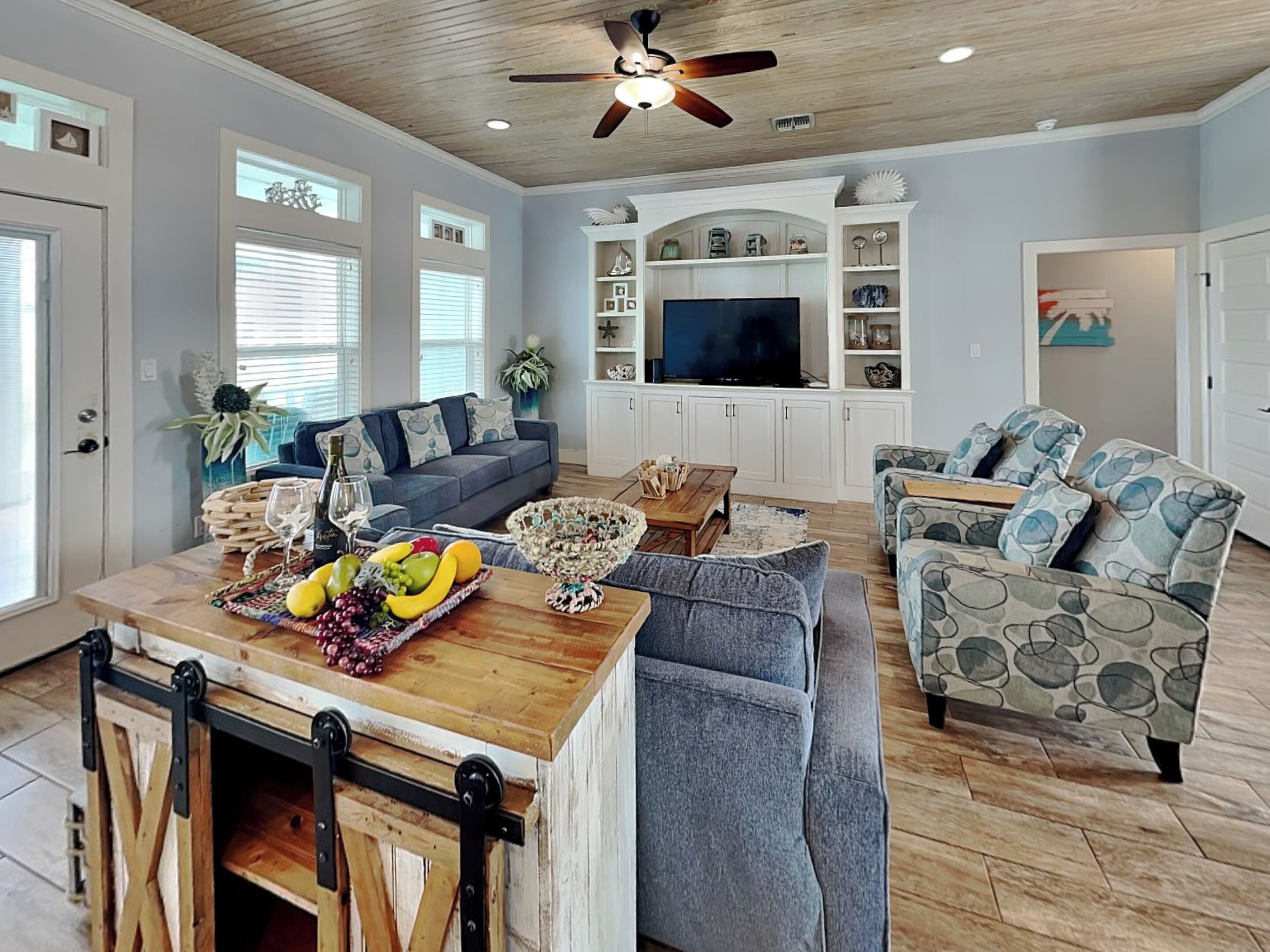 A spacious living room with a wooden ceiling, a large TV, and a dining area with a wooden table and chairs.