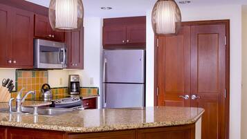 A kitchen with wooden cabinets, stainless steel appliances, a granite countertop, and pendant lighting.