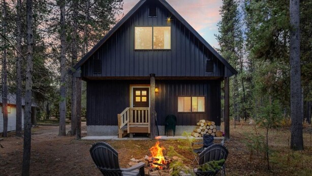 Eine rustikale Holzhütte mit einer Holzterrasse, einer Feuerstelle und zwei Stühlen.