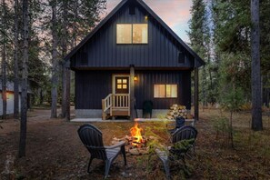 Eine rustikale Holzhütte mit einer Holzterrasse, einer Feuerstelle und zwei Stühlen.