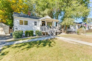 A single-story white house with a front porch, a small front yard, and a mailbox.